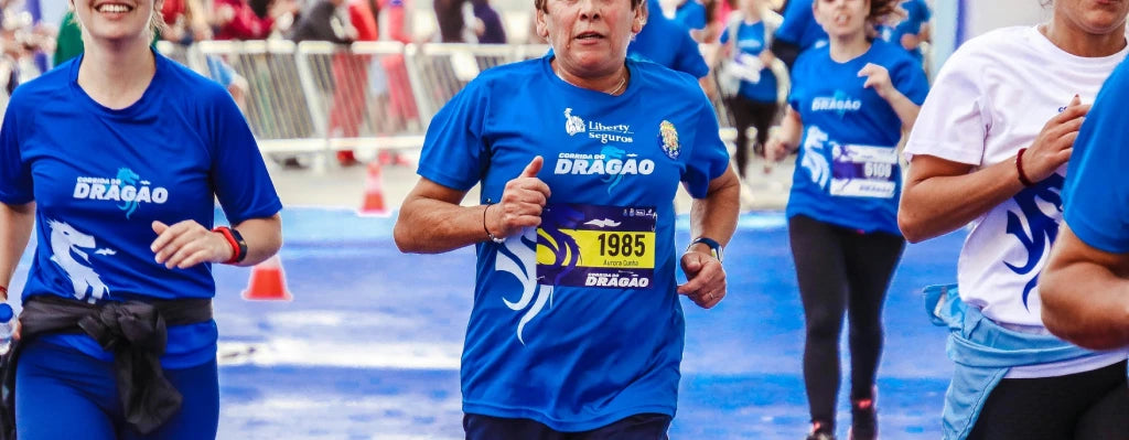 Mehrere Personen nehmen an einem Laufwettbewerb teil, tragen blaue Sportshirts mit "Dragão"-Aufdruck, umgeben von Zuschauern.