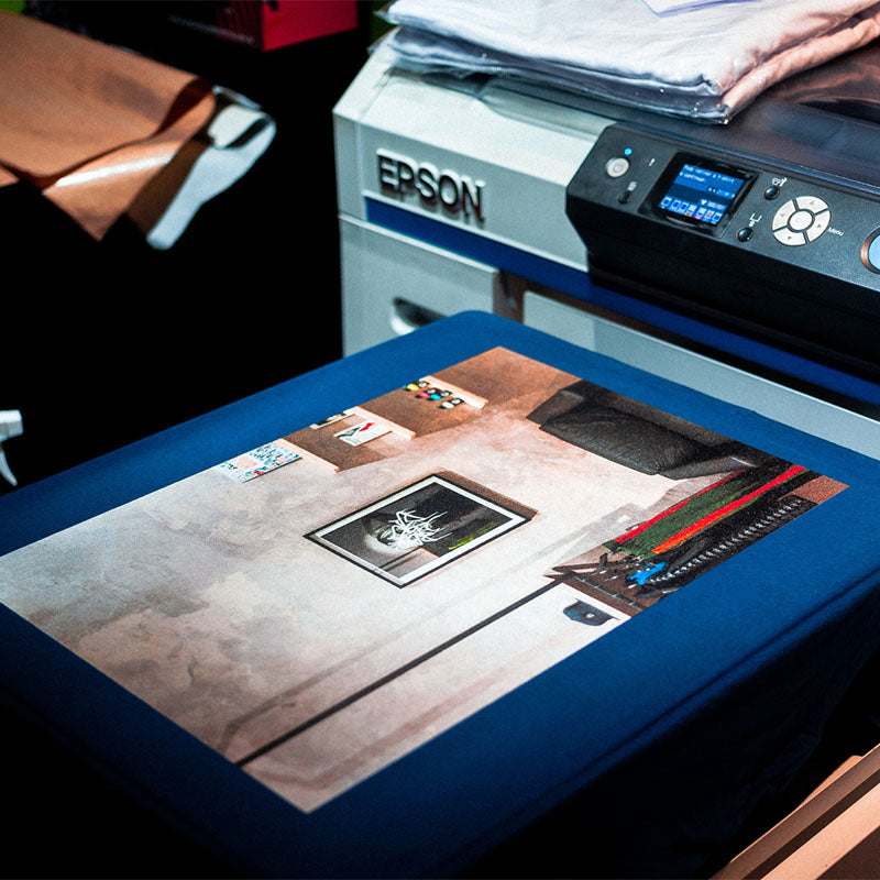 Ein Epson-Drucker erstellt ein Stoffbild. Das Bild zeigt einen Raum mit Werkzeugen und einem gerahmten Poster an der Wand.