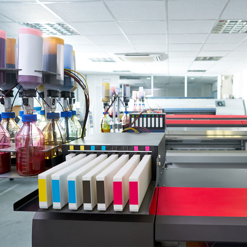 Moderne Digitaldruckmaschine mit farbigen Tintenpatronen und Flaschen in einer professionellen Druckerei, hell erleuchtet.